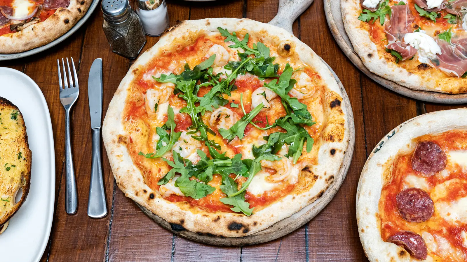 Pizzas from Pizza by Soho on a timber table with cutlery